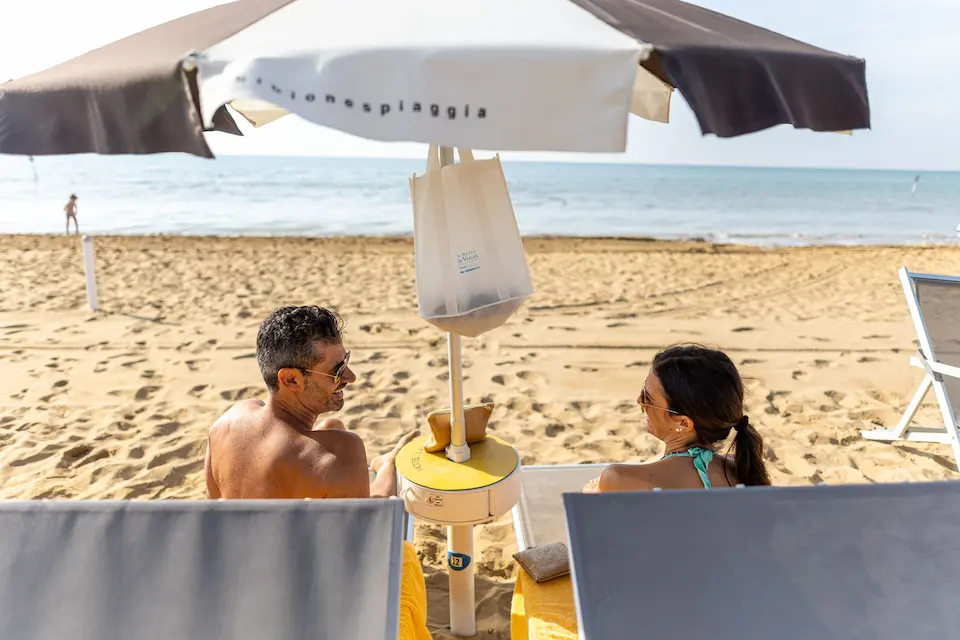 Coppia in spiaggia che si rilassa sotto l'ombrellone a Bibione